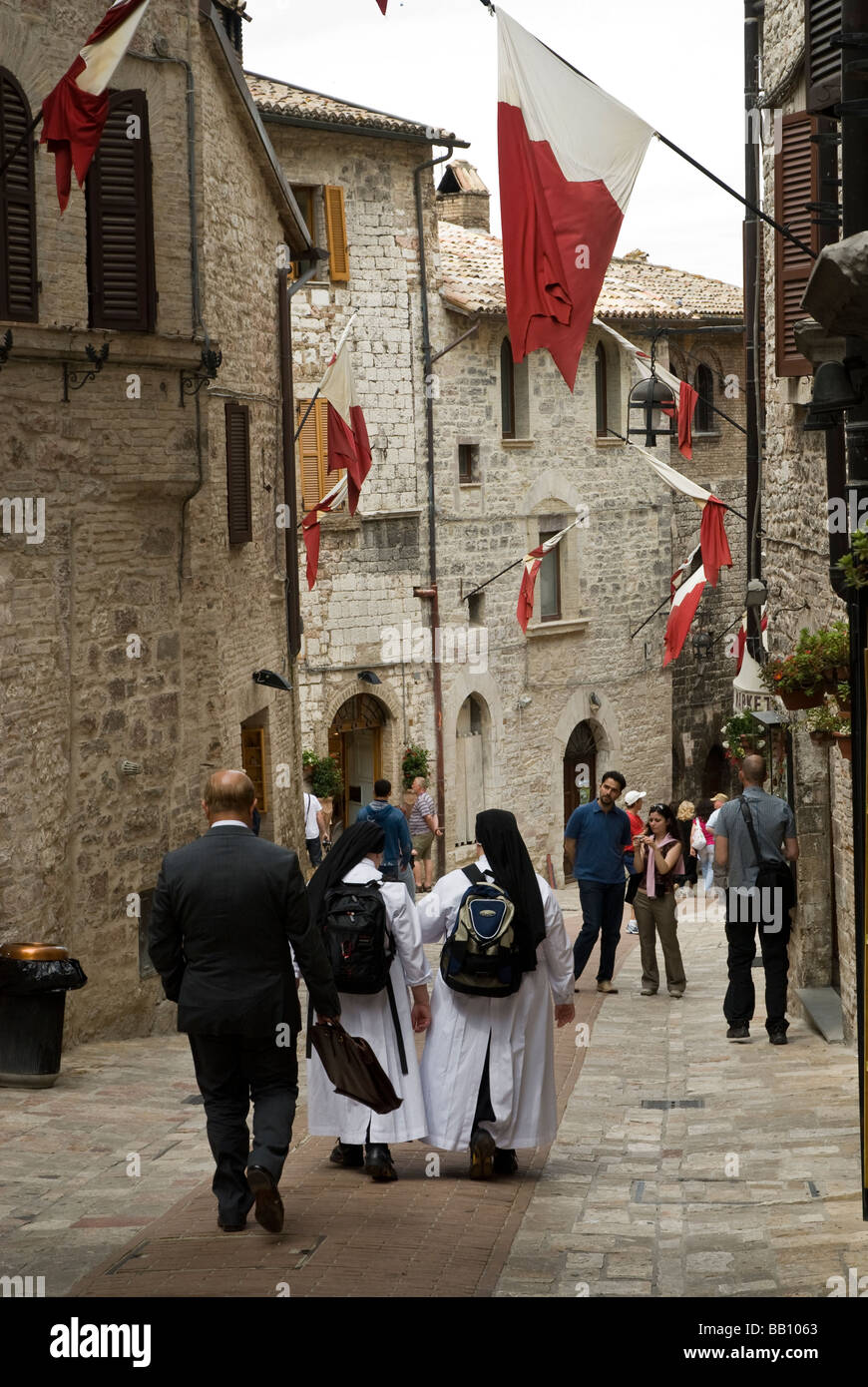 Nonnen und Geschäftsmann auf Straße in Assisi unter Flaggen Stockfoto