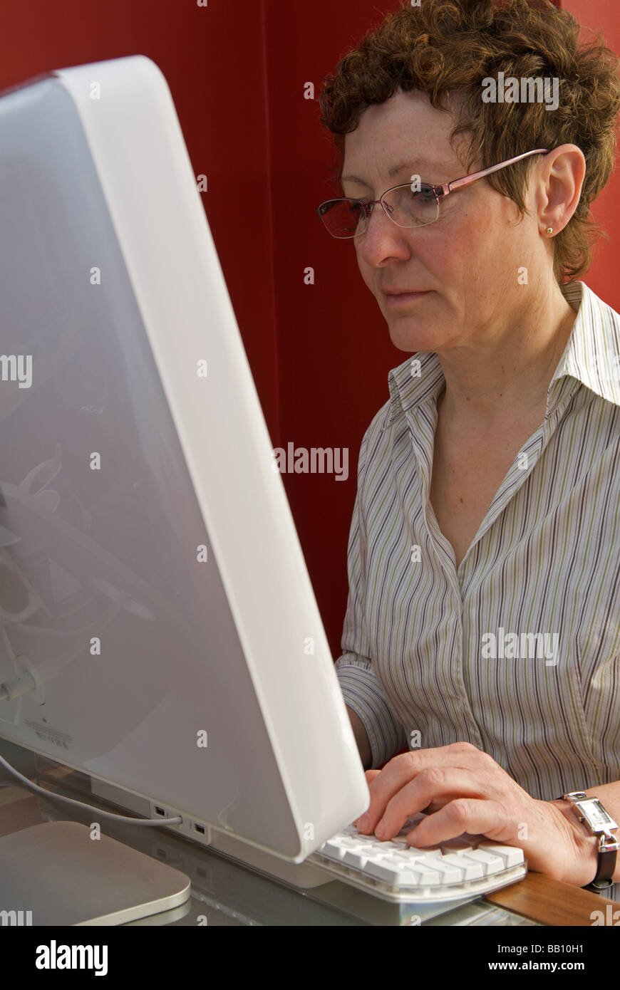 Frau von zu Hause aus mit Hilfe eines Computers Stockfoto
