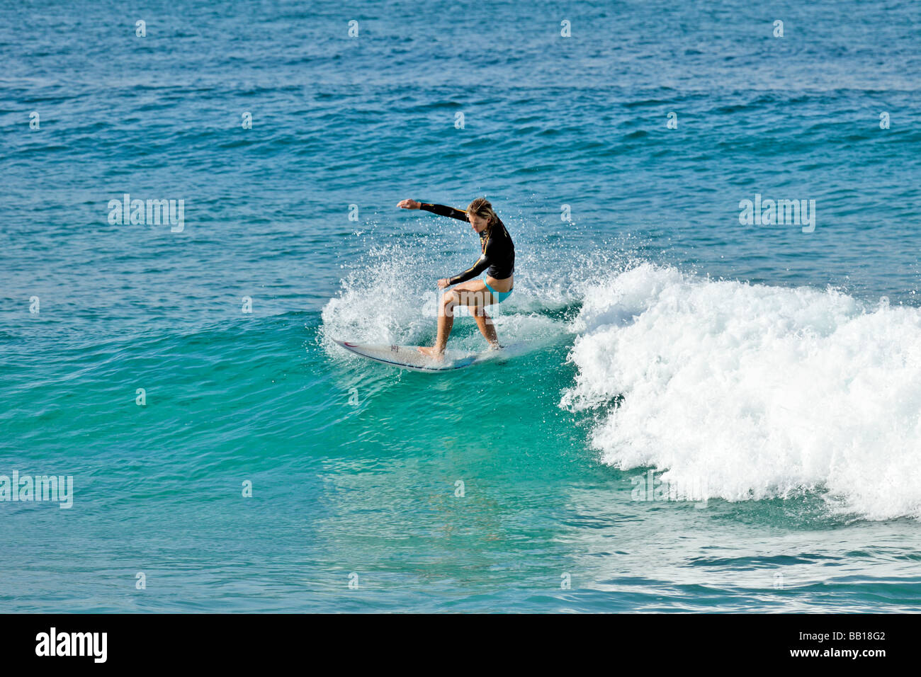 Surfer fängt eine Welle für eine Fahrt ins Ufer am späten Nachmittag Stockfoto