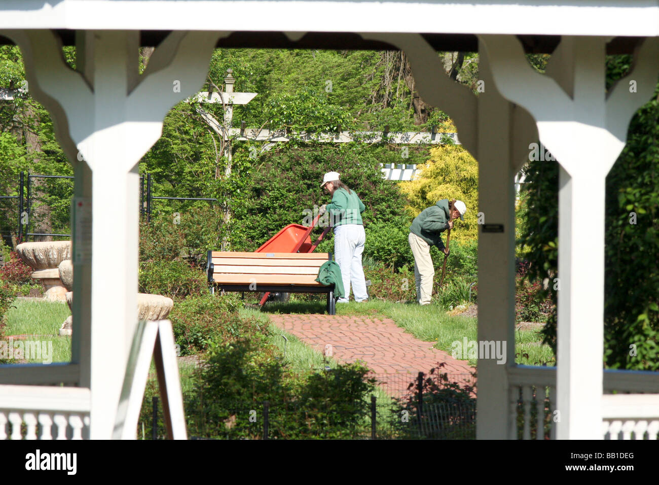 Gärtner in einem Rosengarten mit Schubkarre und Werkzeugen arbeiten