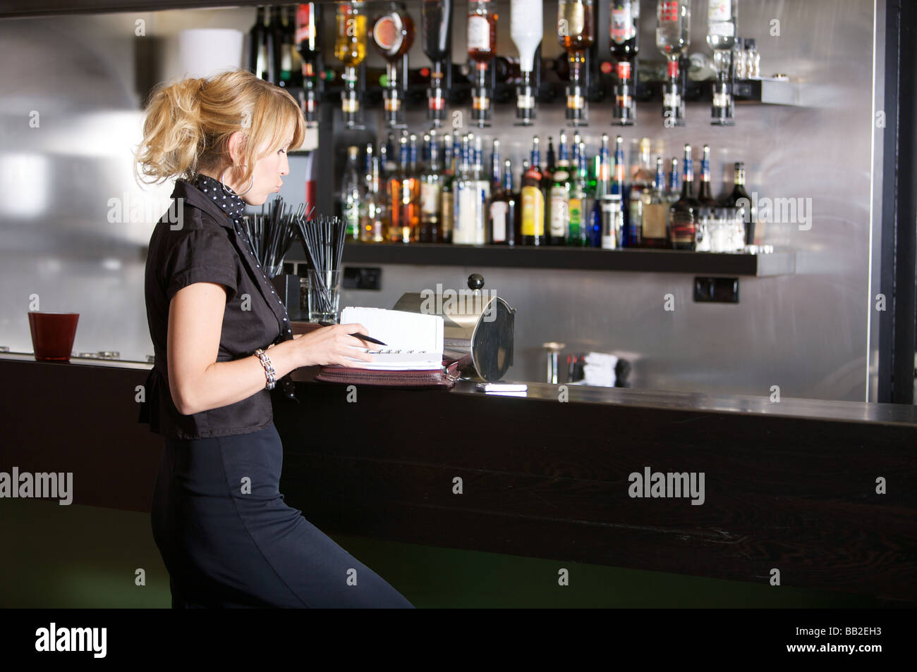 Geschäftsfrau, die in einer Bar stehend arbeiten auf ihren Kalender Stockfoto