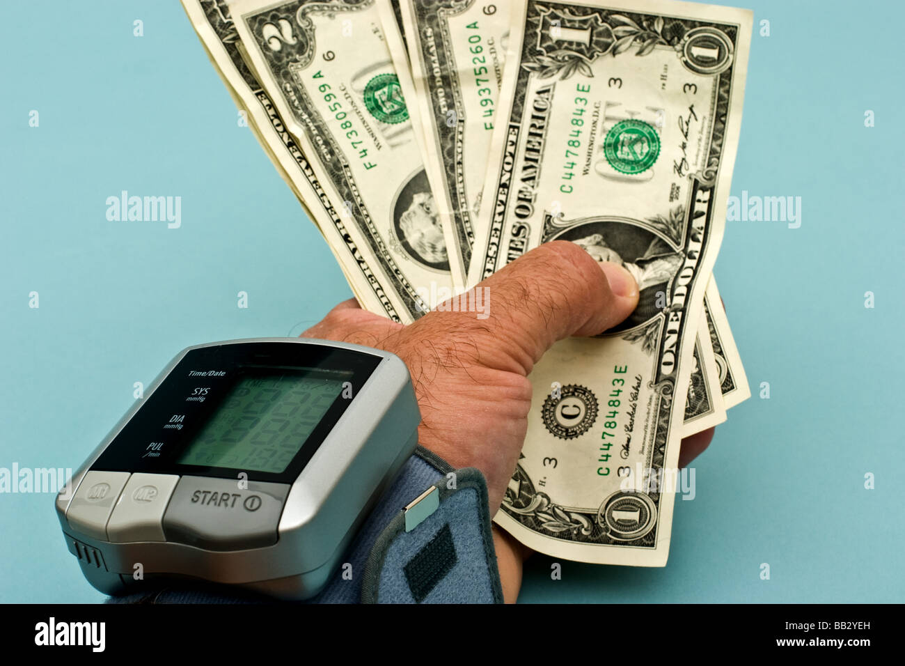 Personen-Hand mit Dollarnoten mit einer Blutdruckmanschette am Handgelenk Stockfoto