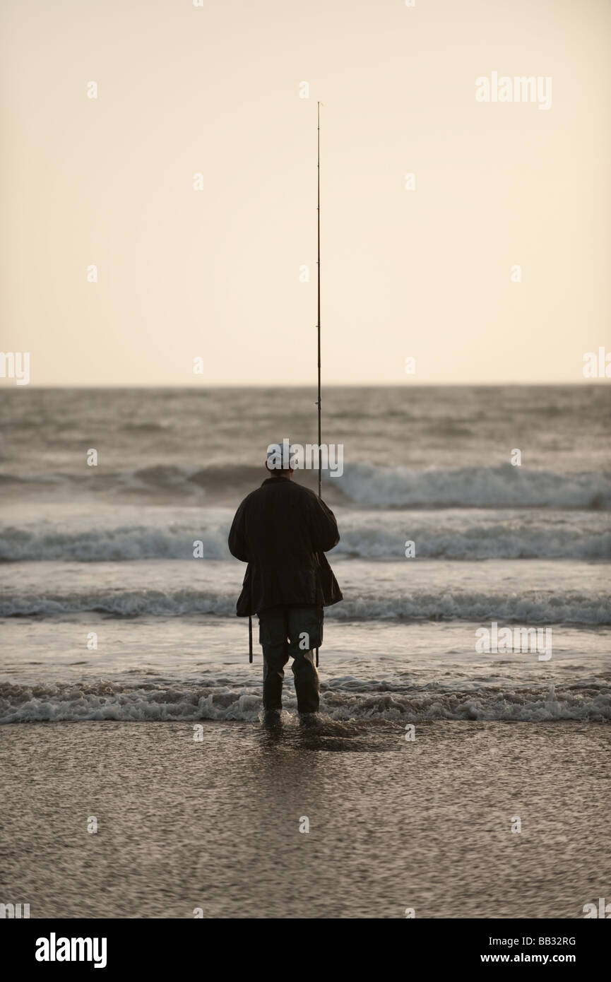 Ein Mann alleine Angeln auf Wolfsbarsch mit einem Stab und Linie am Strand in Borth Ceredigion Cardigan Bay Küste von Wales UK Stockfoto