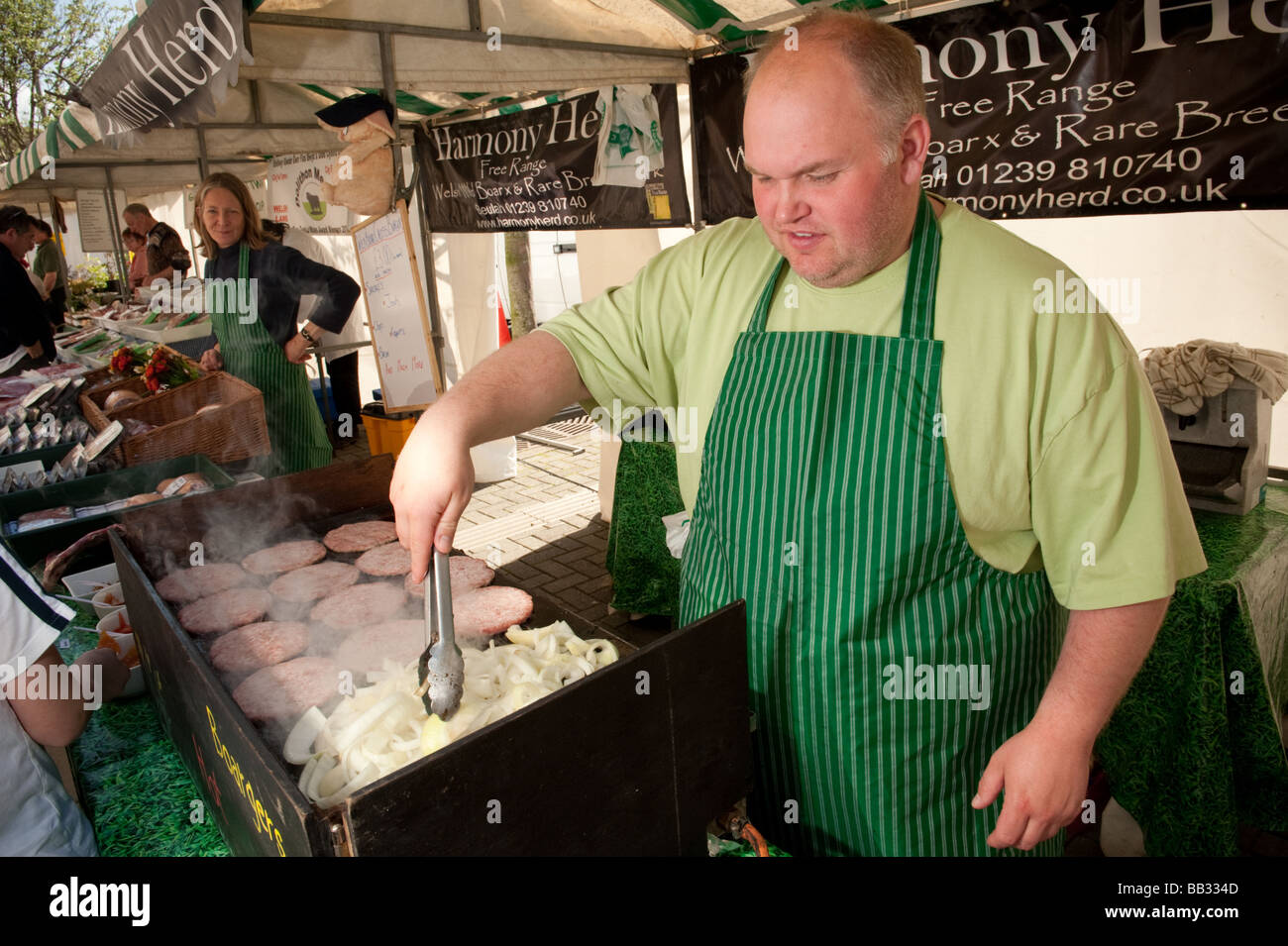 Stattlicher Mann Kochen Bio Freilandhaltung Schweinefleisch Burger auf einem Marktstand Aberystwyth Bauernmarkt Wales UK Stockfoto