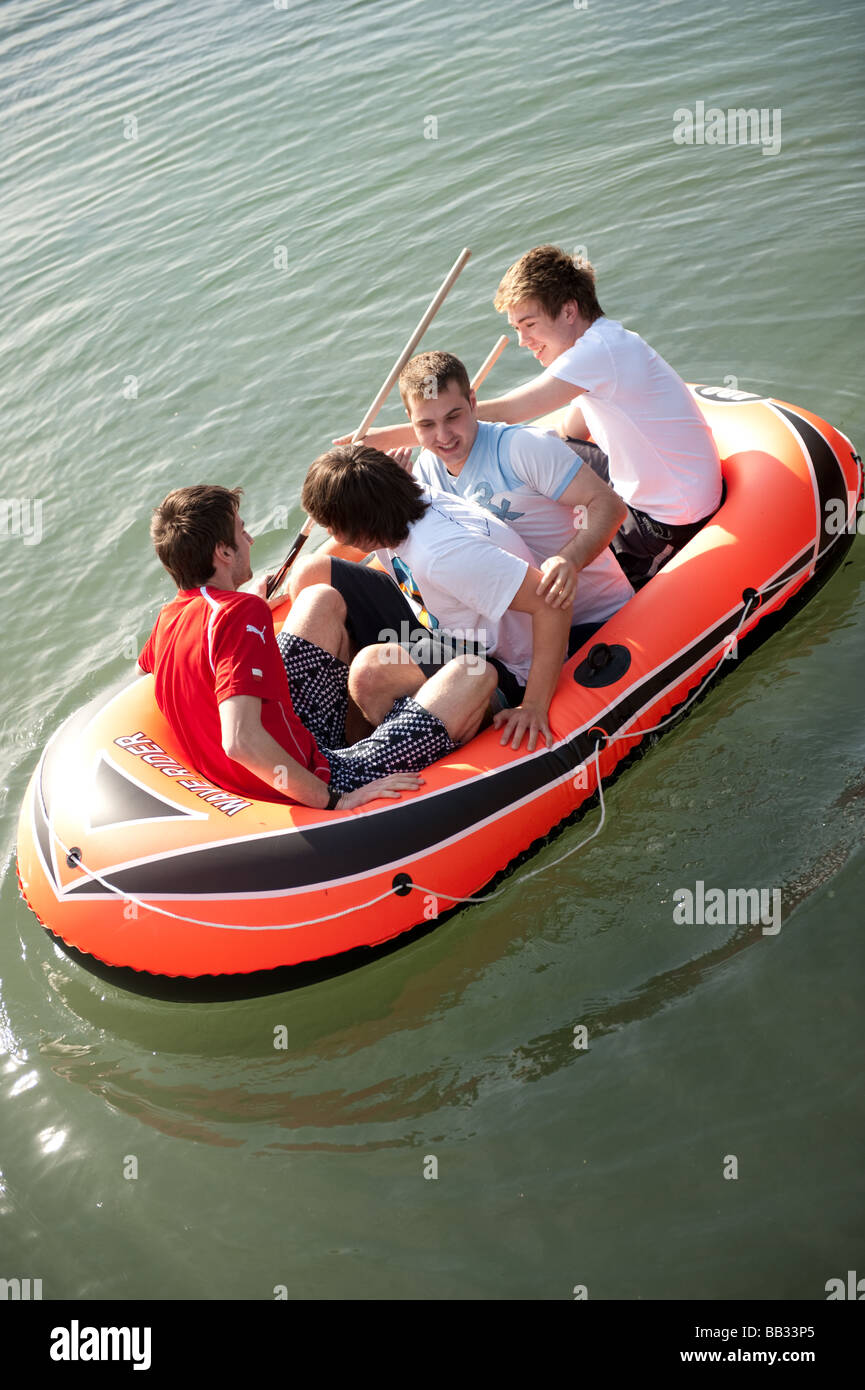 Vier junge Männer Teenager Studenten an der Aberystwyth University Spaß auf dem Wasser paddeln in ein Schlauchboot, Wales UK Stockfoto