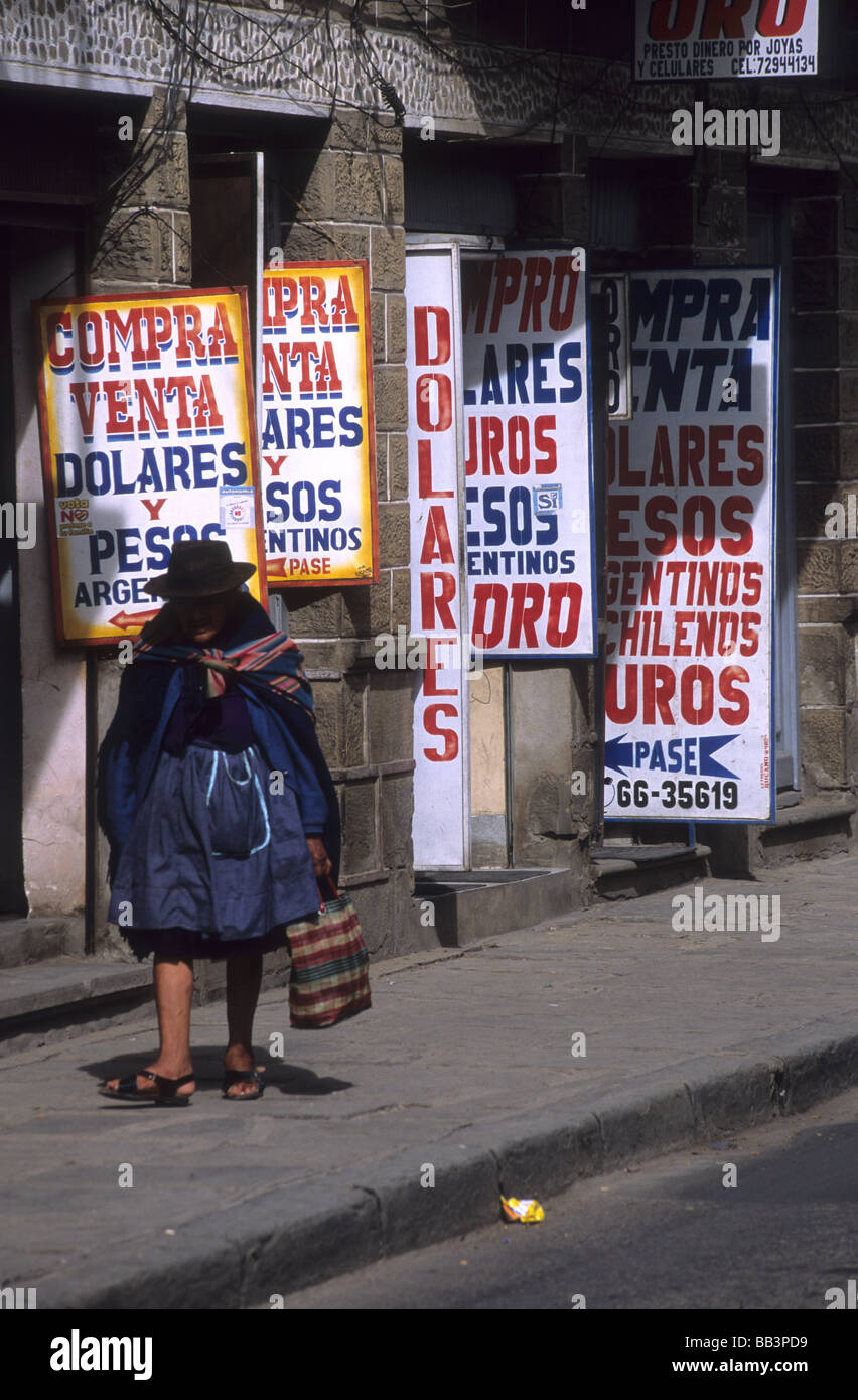 Indigenen Quechua-Dame zu Fuß entlang der Straße voller Geldwechsler Ladenschilder, Tarija, Bolivien Stockfoto