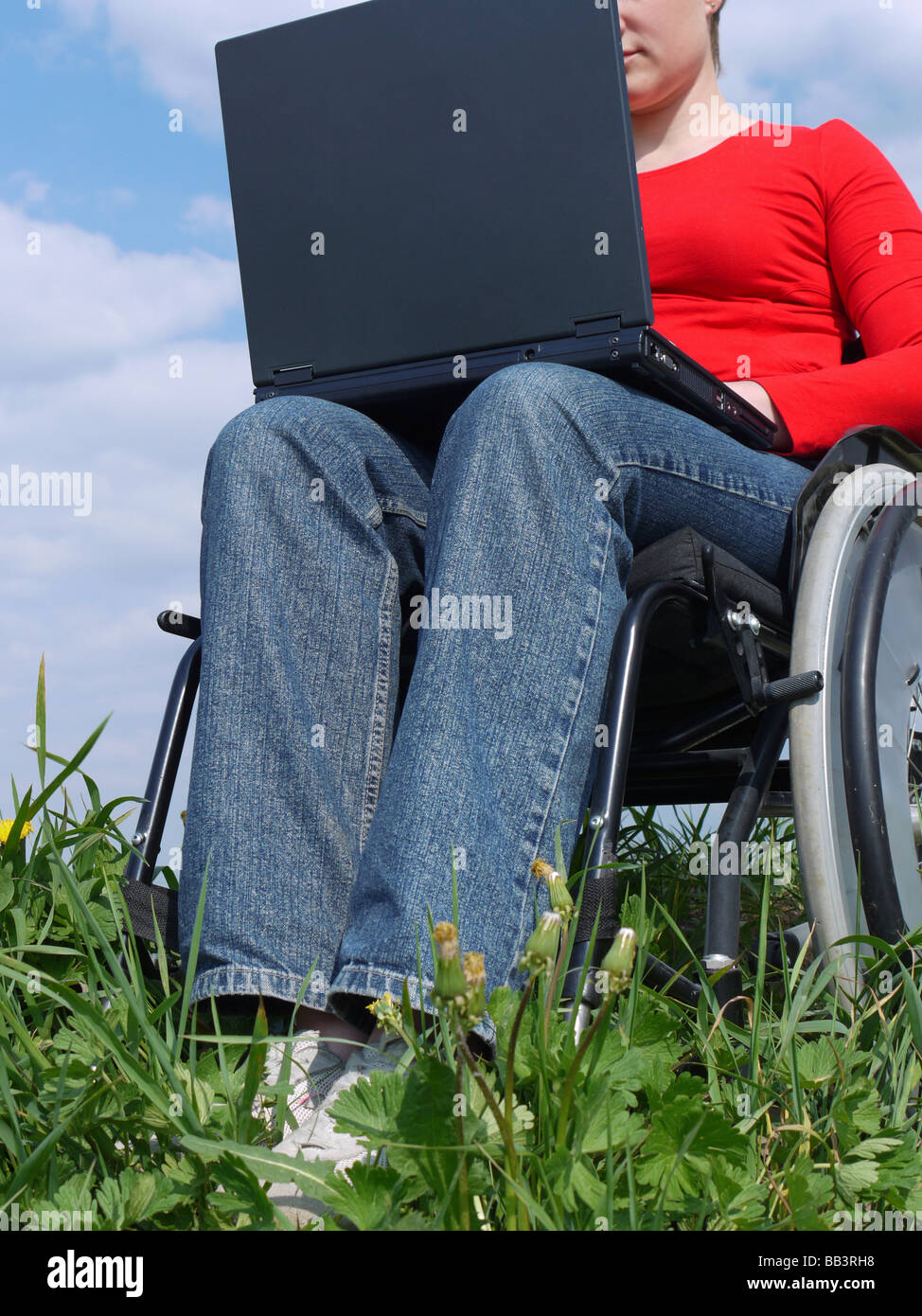 Behinderte Frau im Rollstuhl mit Laptop im freien Stockfoto