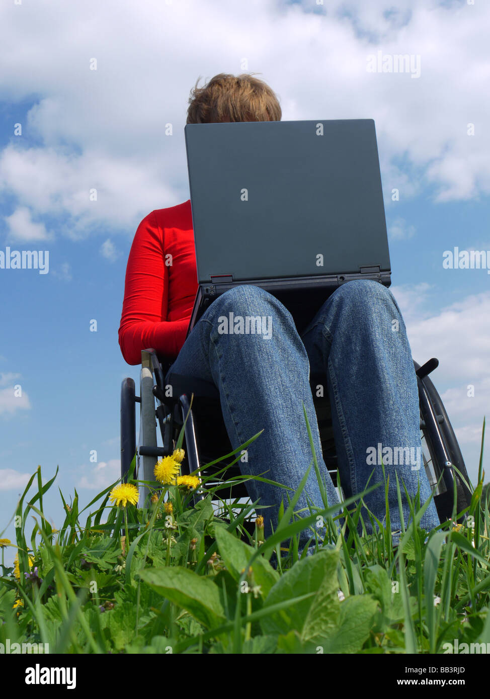 Behinderte Frau im Rollstuhl mit Laptop im freien Stockfoto