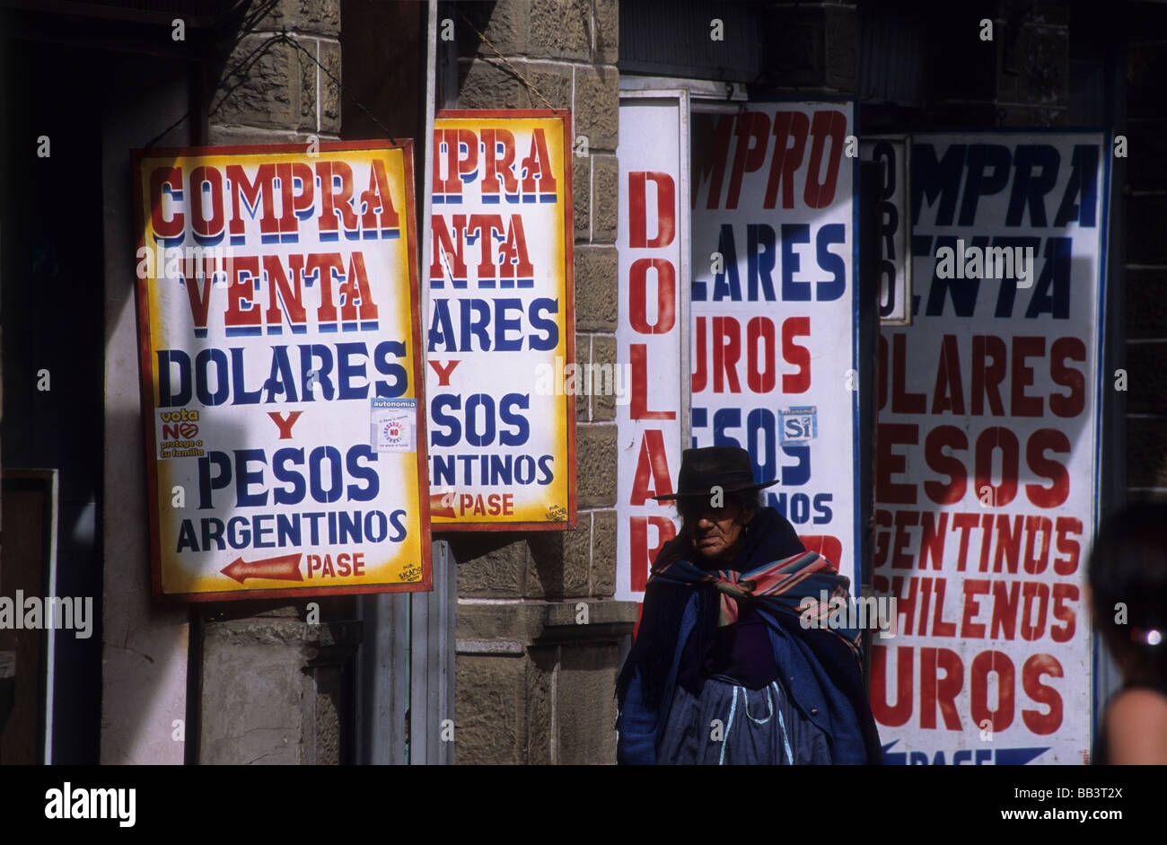 Indigenen Quechua-Dame zu Fuß entlang der Straße voller Geldwechsler Ladenschilder, Tarija, Bolivien Stockfoto