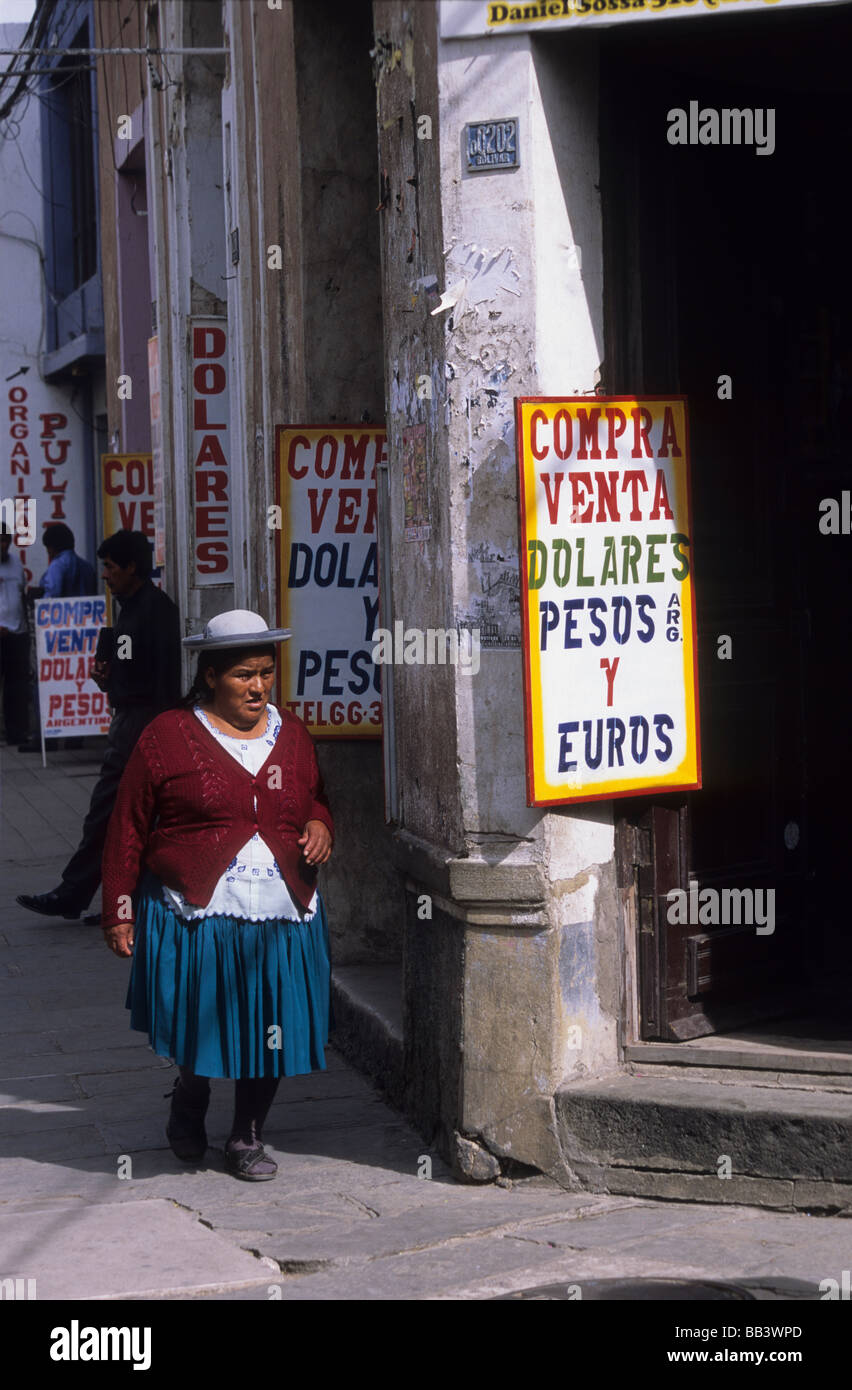 Lokalen indigenen Quechua-Dame zu Fuß entlang der Straße voller Geldwechsler Ladenschilder, Tarija, Bolivien Stockfoto