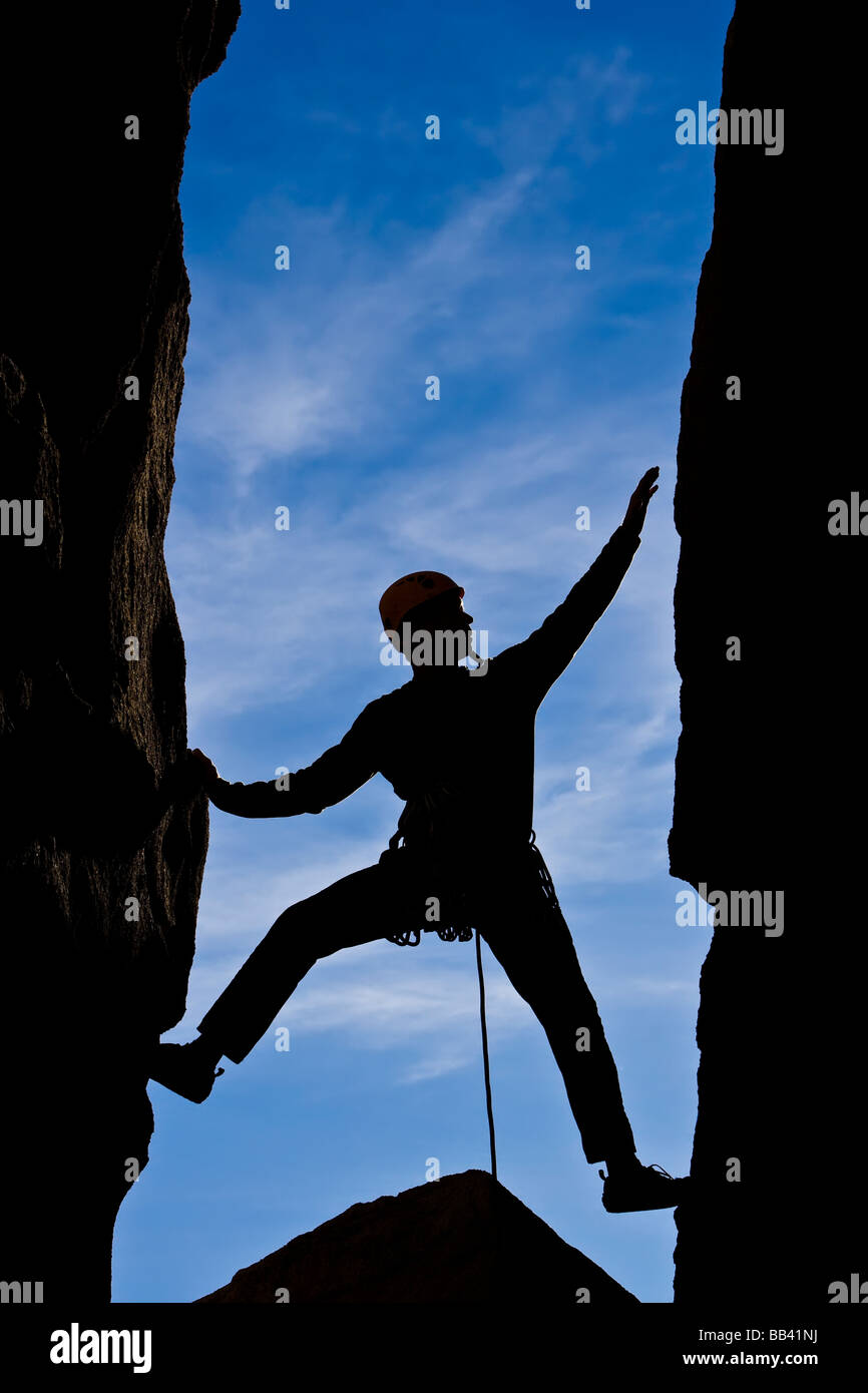 Kletterer Brücken seinen Weg über einen Spalt auf einem steilen Felsen Stockfoto