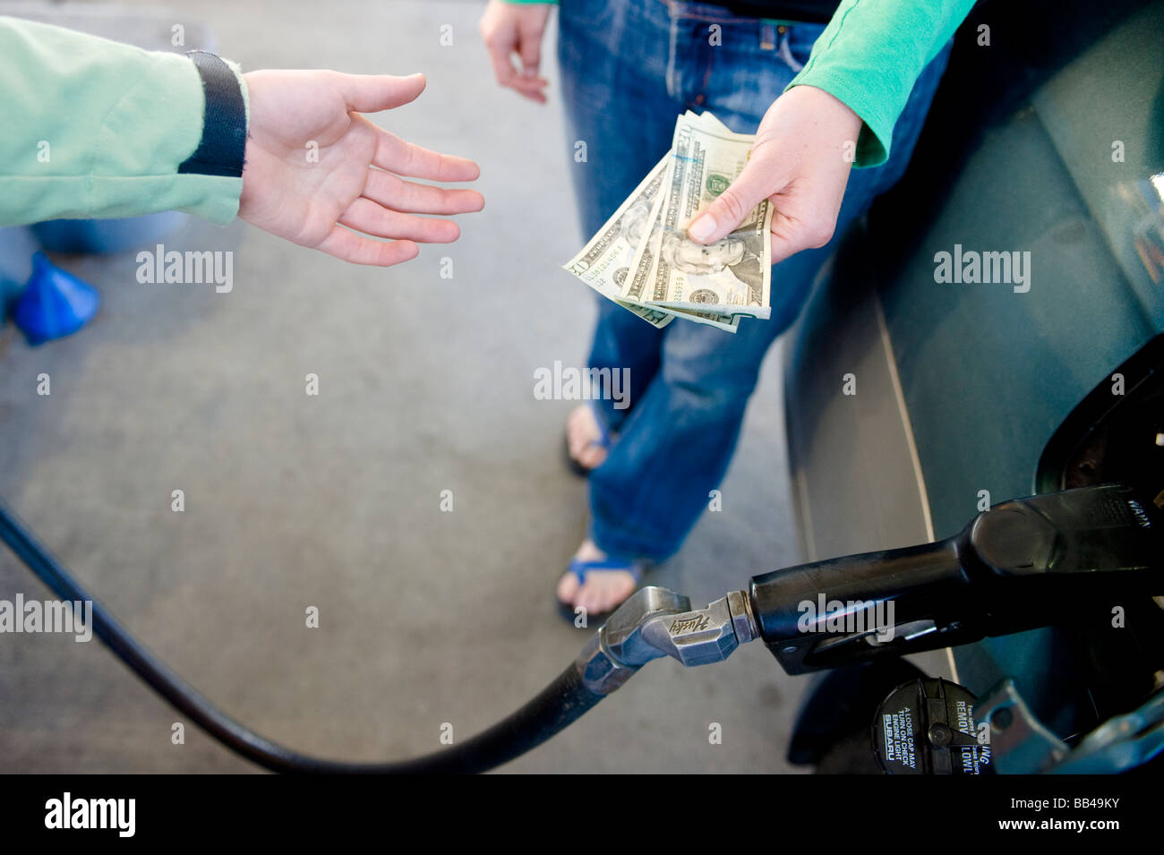 Close up Portrait of a young Woman es Hände, Übergabe von Geld für Benzin an der Station Attendant in Bend, Oregon. Stockfoto
