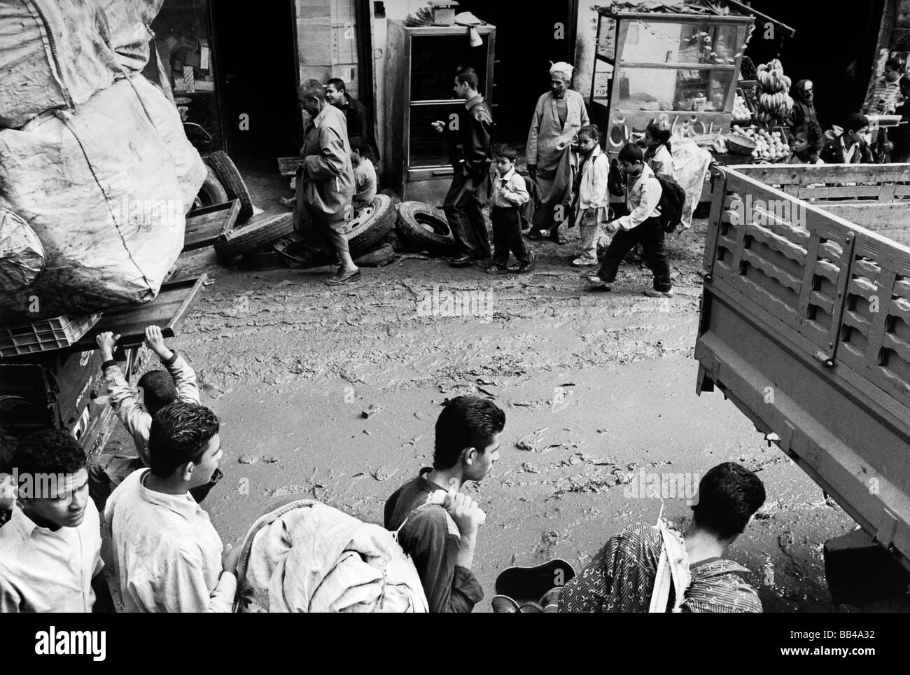 Menschen gehen einer schlammigen Straße im Stadtteil Zabaleen am Mokattam Hügel in Kairo, Ägypten. Stockfoto