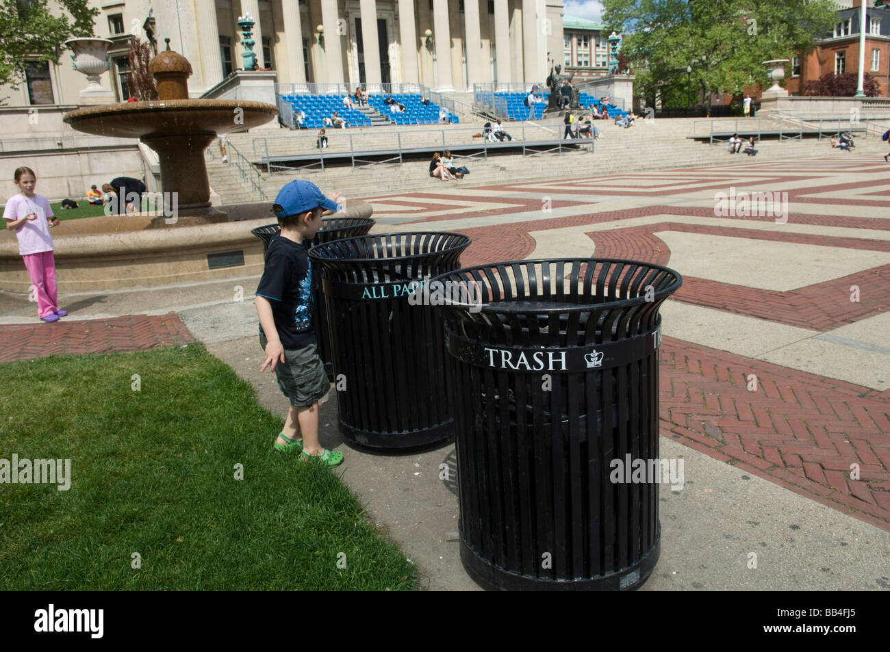 Ein kleiner Junge recycelt in einem Papierkorb auf dem Campus der Columbia University in New York Stockfoto