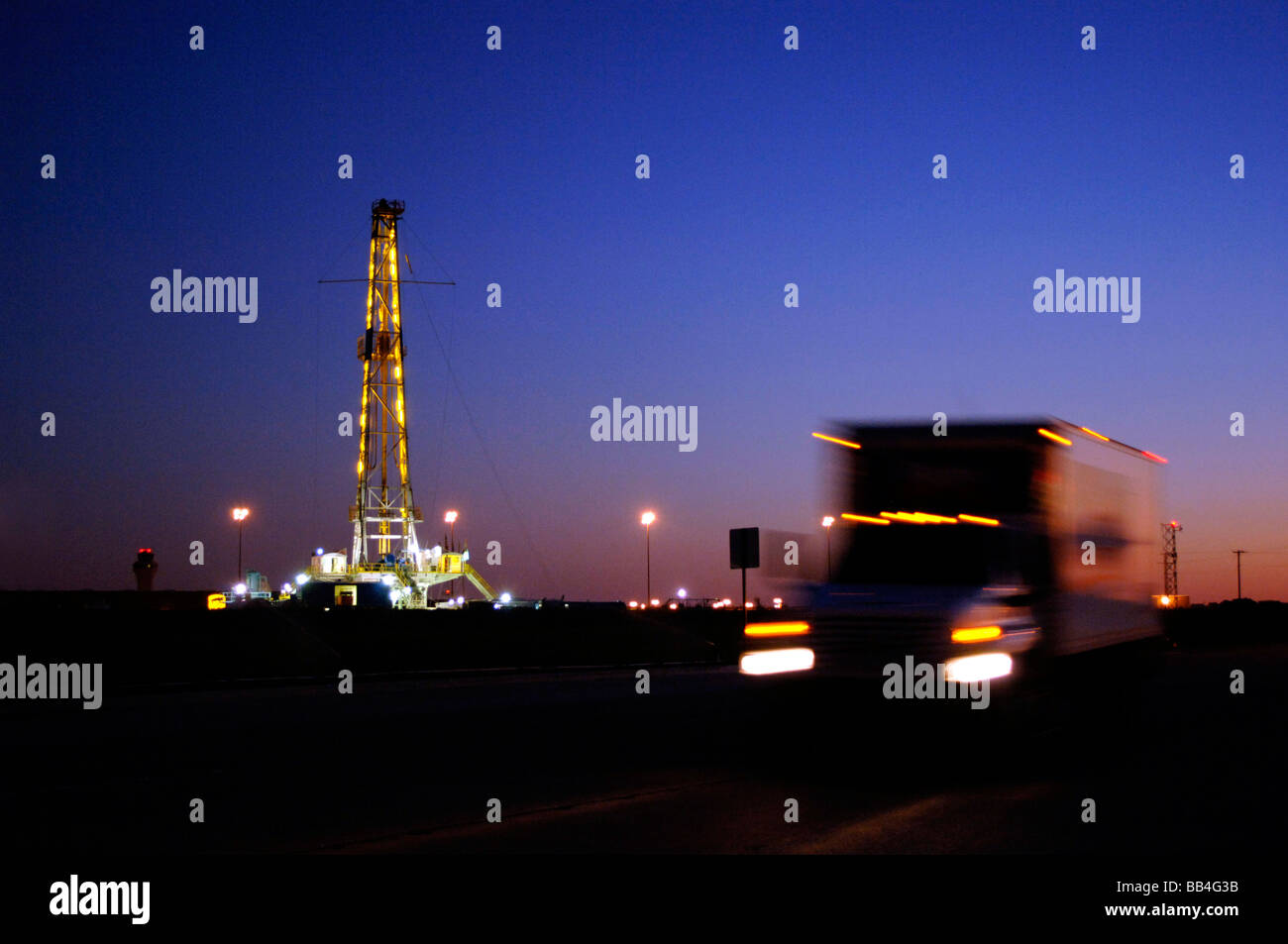 Verschwommene LKW Rennen durch Öl Derrick in einer Zeit eine intensive Suche nach Alternativen erneuerbaren, grüne Energie in einem Texas in der Abenddämmerung Stockfoto