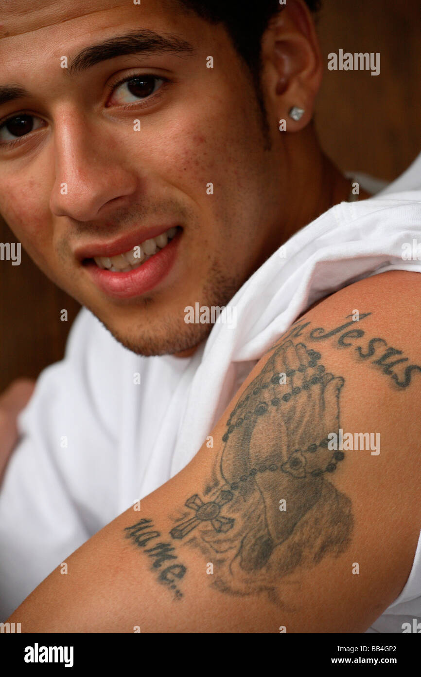 Eine religiöse Tattoo auf einem jungen spanischen Studenten-Arm, der liest Stockfoto