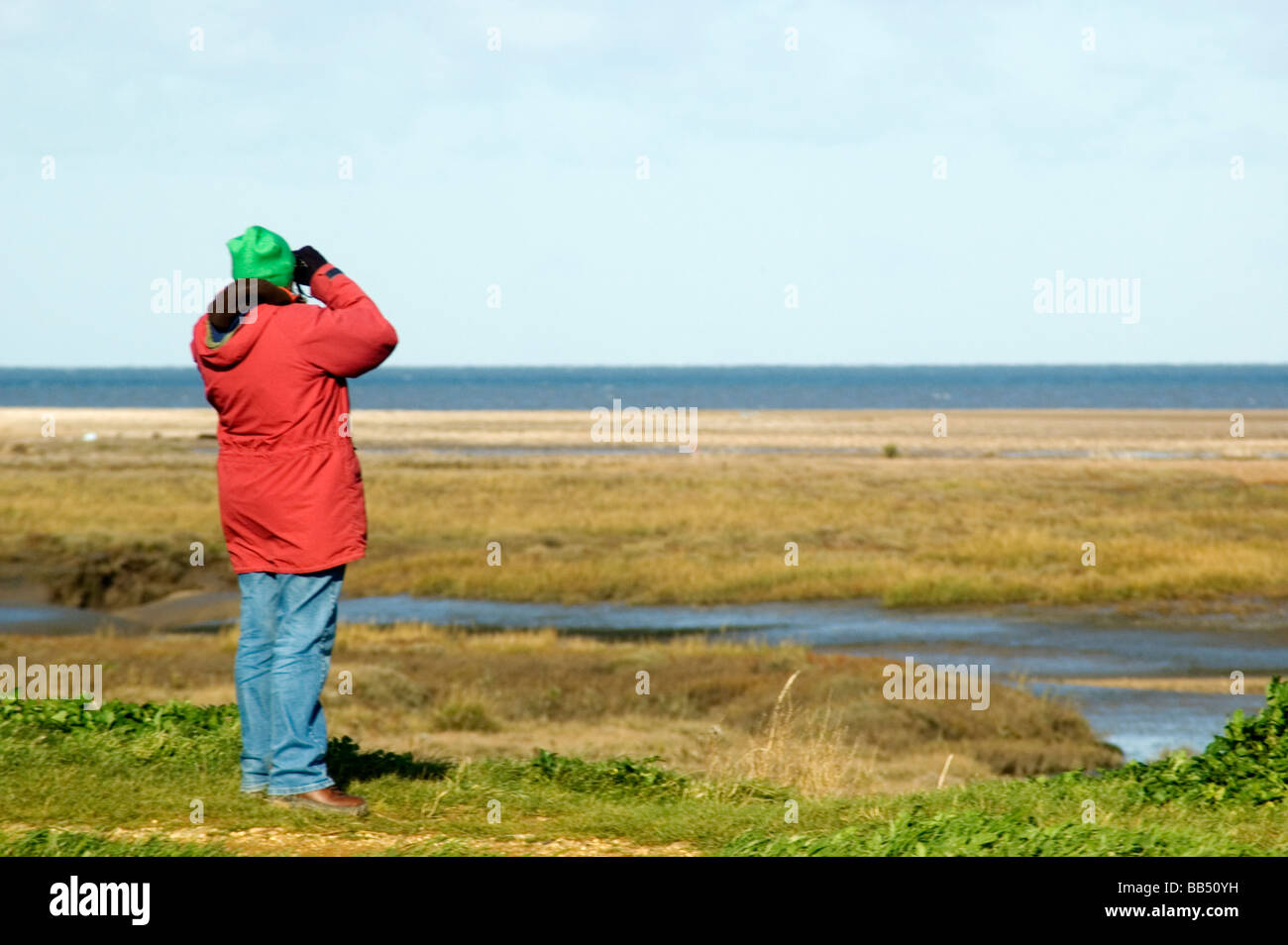 Weibliche Vogelbeobachter Blick durch ein Fernglas auf der North Norfolk-Küste. Stockfoto