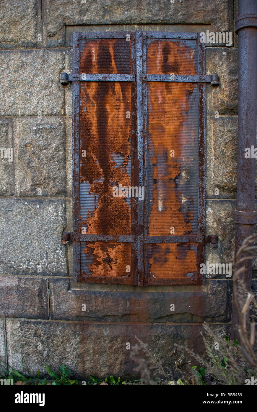 Rostes rostiges Eisen Fensterläden Steinmauer antike Ruine bauen alte vertikal Stockfoto
