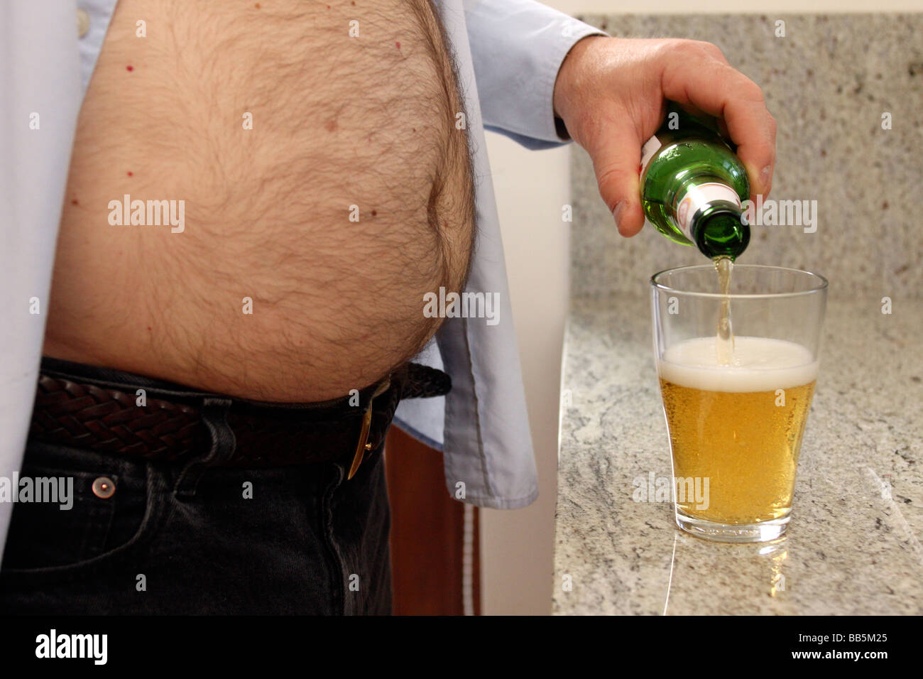 Mann mittleren Alters mit Bierbauch Gießen einen drink Stockfoto