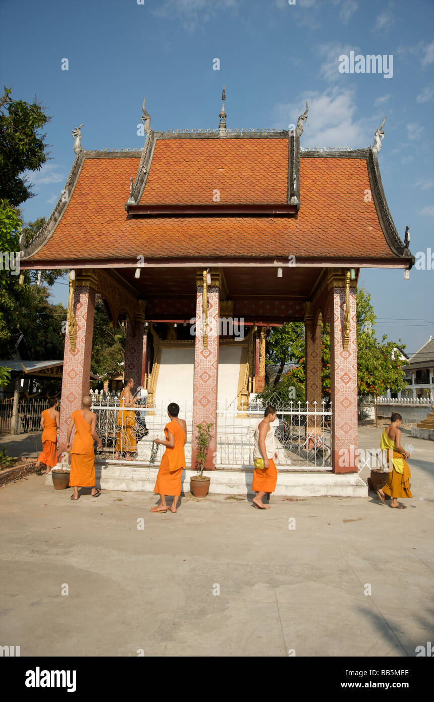 Buddhistische Mönche gehen über ihre täglichen Aufgaben des Tempels zu Reinigungs- und Wartungsarbeiten in Luang Prabang Stockfoto