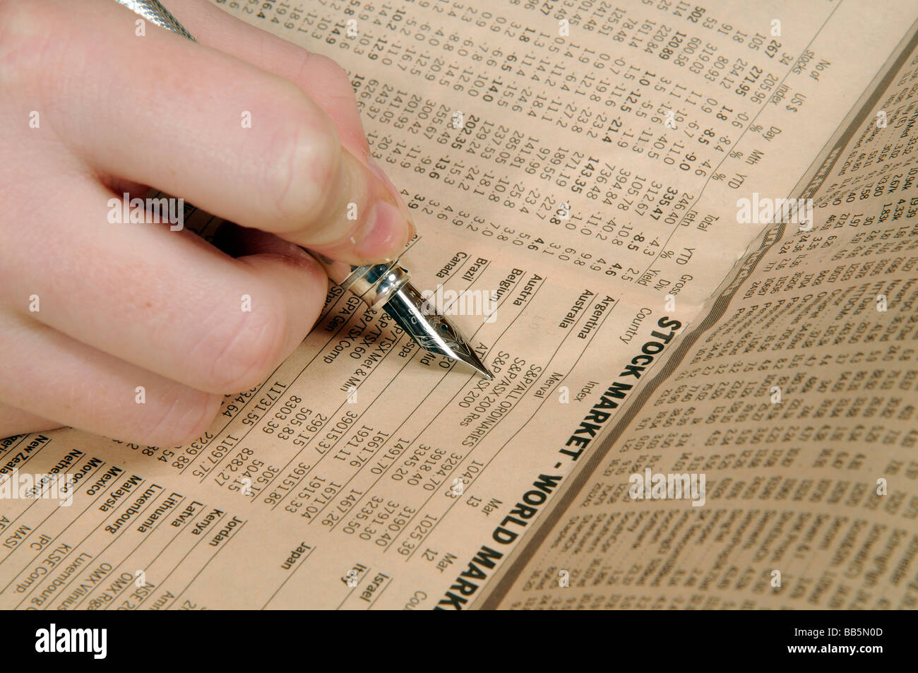 Hand, die einen Silberstift Weltmarktpreise von einer Finanzzeitung Seite überprüfen Stockfoto