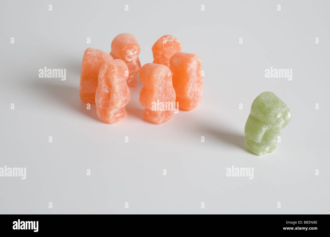 Grüne Gelee Baby aus Gruppe von orange Gummibärchen ausgeschlossen wird. Stockfoto