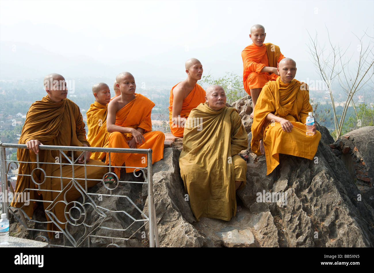 Buddhistische Mönche sitzen auf den Felsen auf dem Gipfel der Hügel Phou Si über Luang Prabang Laos Stockfoto