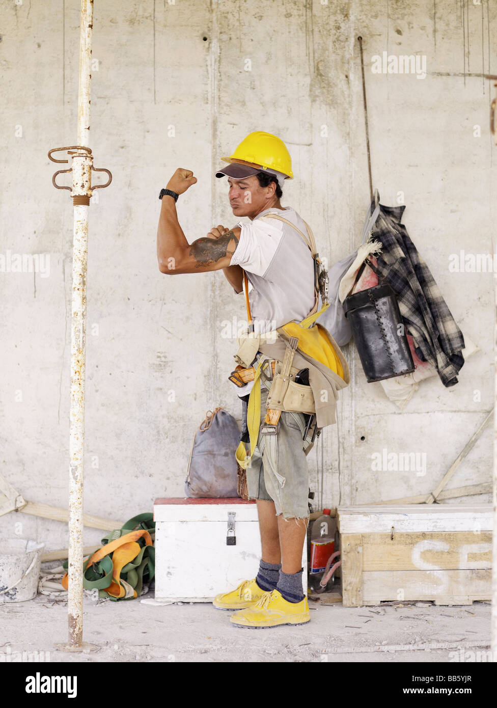 Hispanische Arbeiter beugen Bizeps auf Baustelle Stockfoto