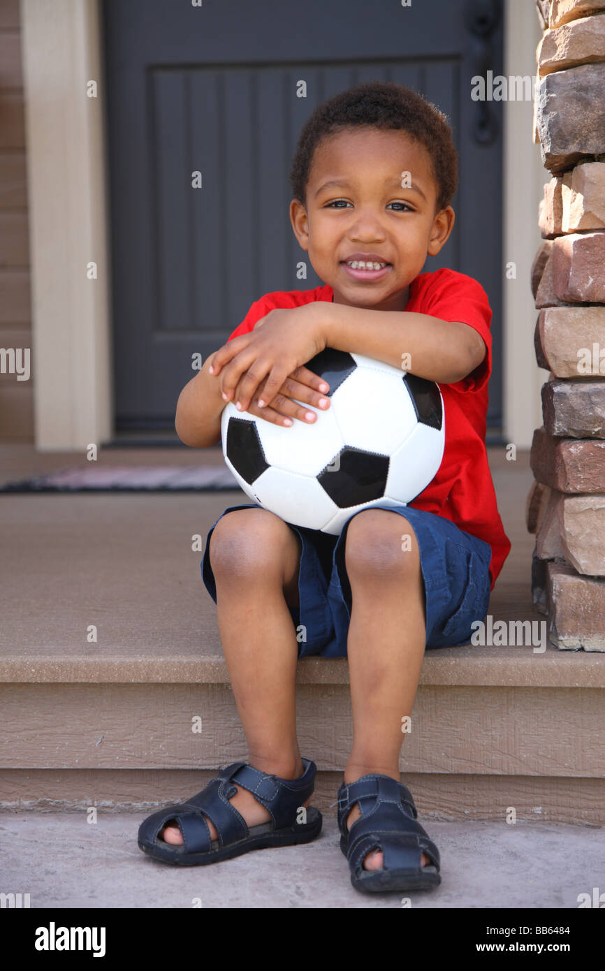 Kleiner Junge mit Fußball auf Veranda Stockfoto