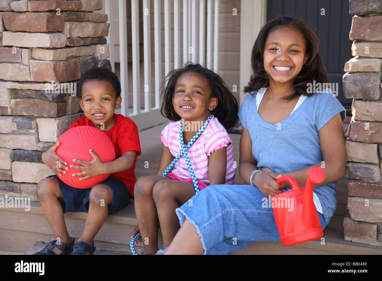 Drei Kinder mit Spielzeug auf Veranda Stockfoto