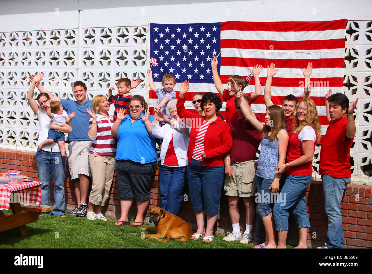 Große Gruppe von Menschen vor amerikanischen Flagge winken Hände Stockfoto