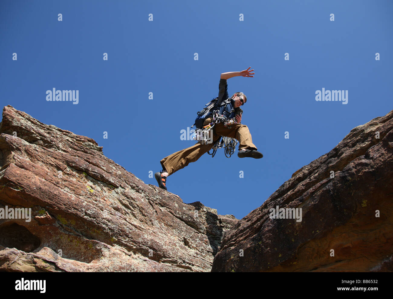 Kletterer springt über Felsen Stockfoto