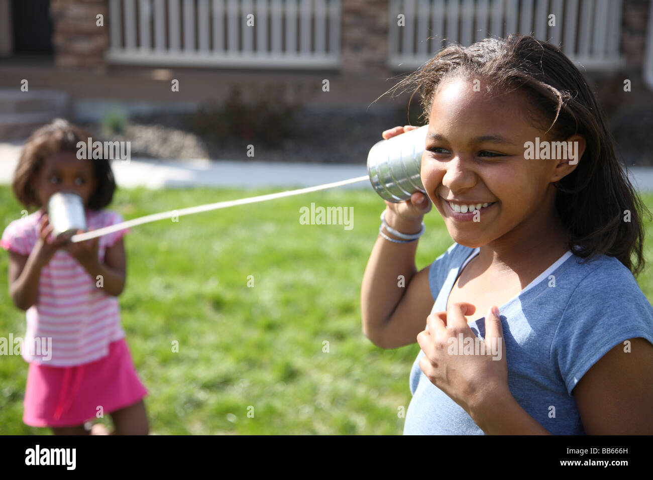 Zwei junge Mädchen spielen Telefon mit Dosen und string Stockfoto
