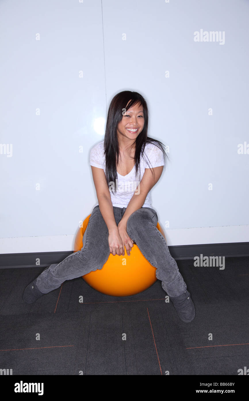 Asiatische Frau sitzen auf orange Kugel Lächeln Stockfoto