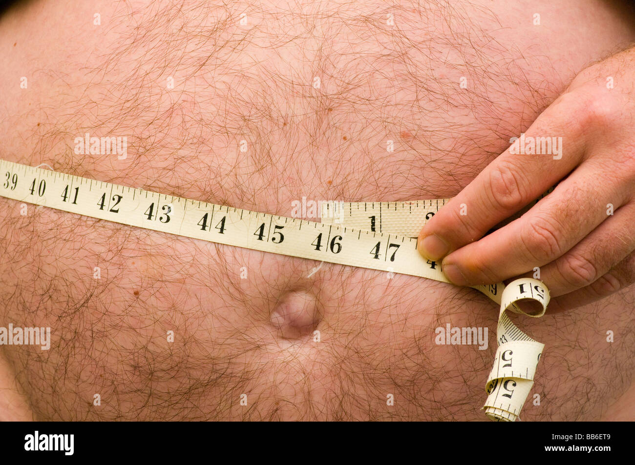 Übergewichtige Menschen messen seine Taille mit einem Maßband Stockfoto