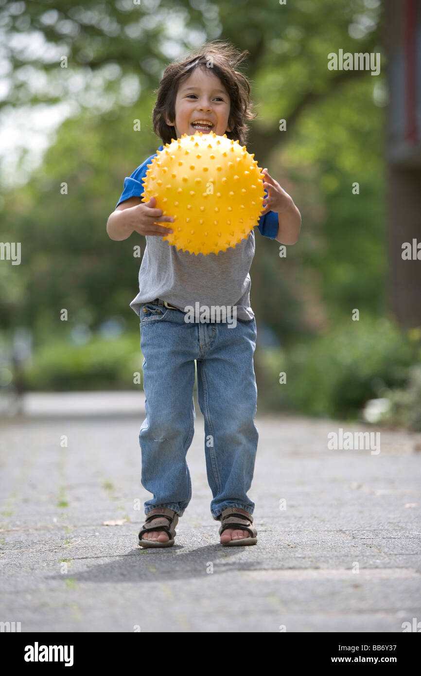 Kleiner Junge einen gelben Ball fangen Stockfoto