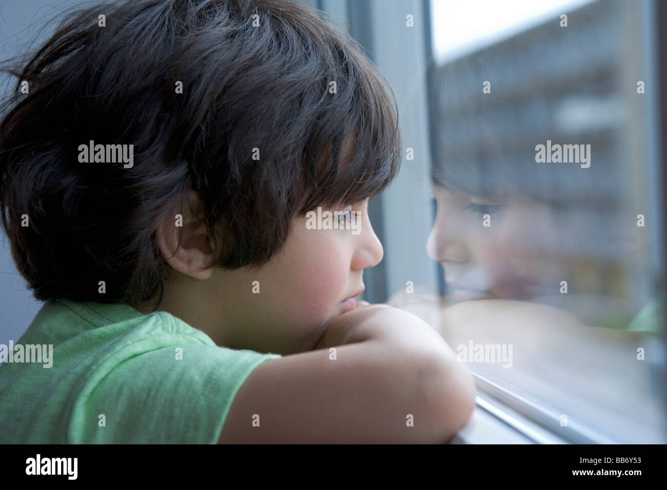 Einsame kleine Junge aus dem Fenster Stockfoto