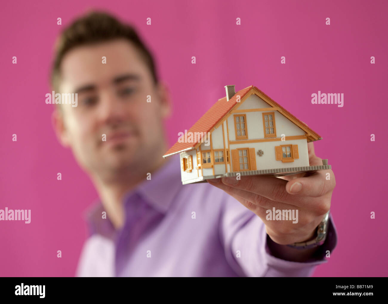 Junger Mann hält ein kleines Haus Stockfoto