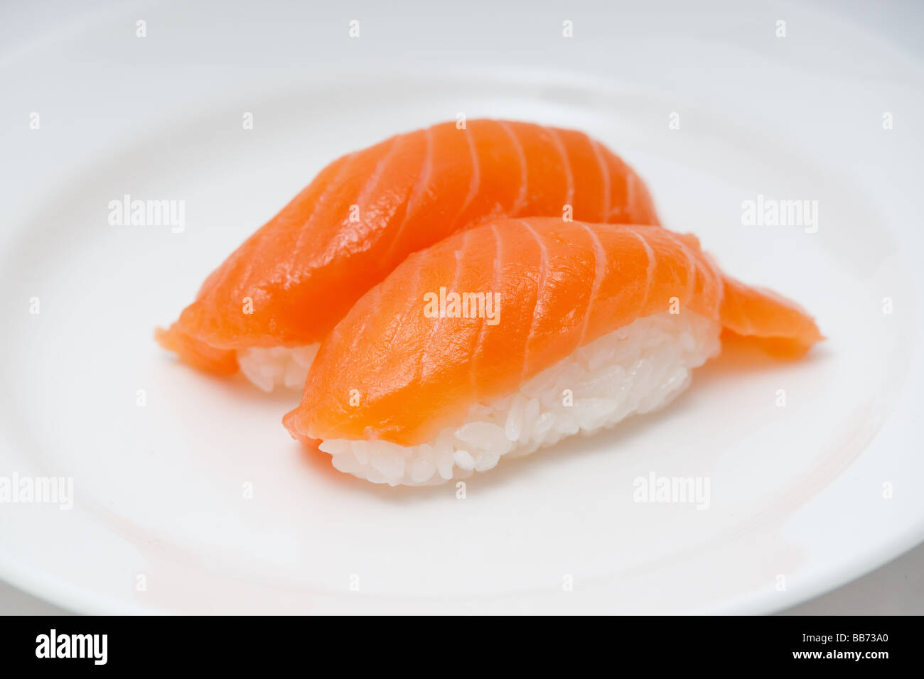 Einem weißen Teller mit zwei Stücken von Lachs Sushi, Nigiri Sashimi auf Betten von Reis. Stockfoto