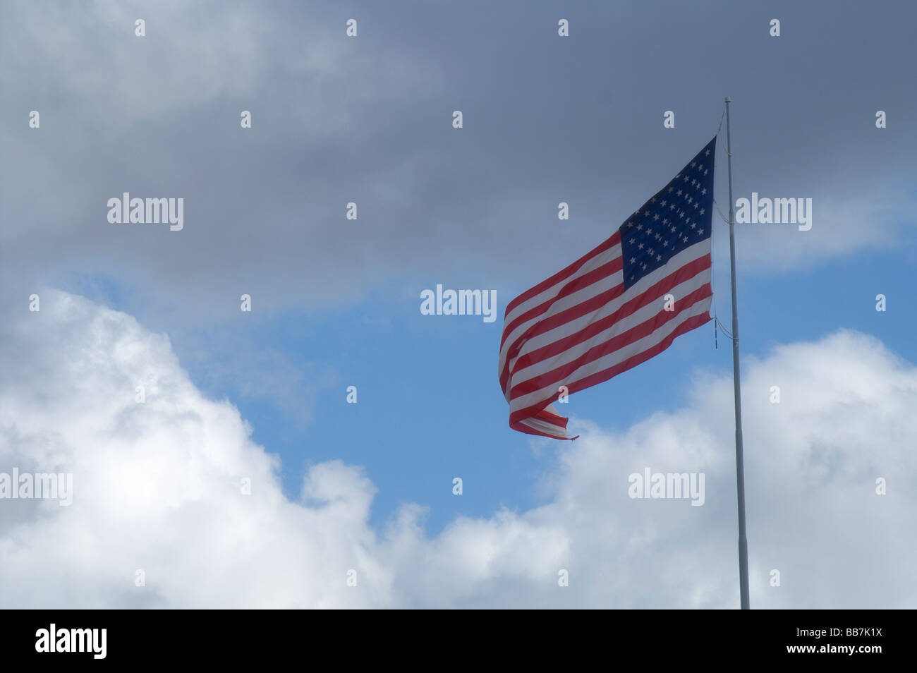 Amerikanische Flagge fliegt hoch in den blauen Himmel mit flauschigen weißen Wolken Stockfoto