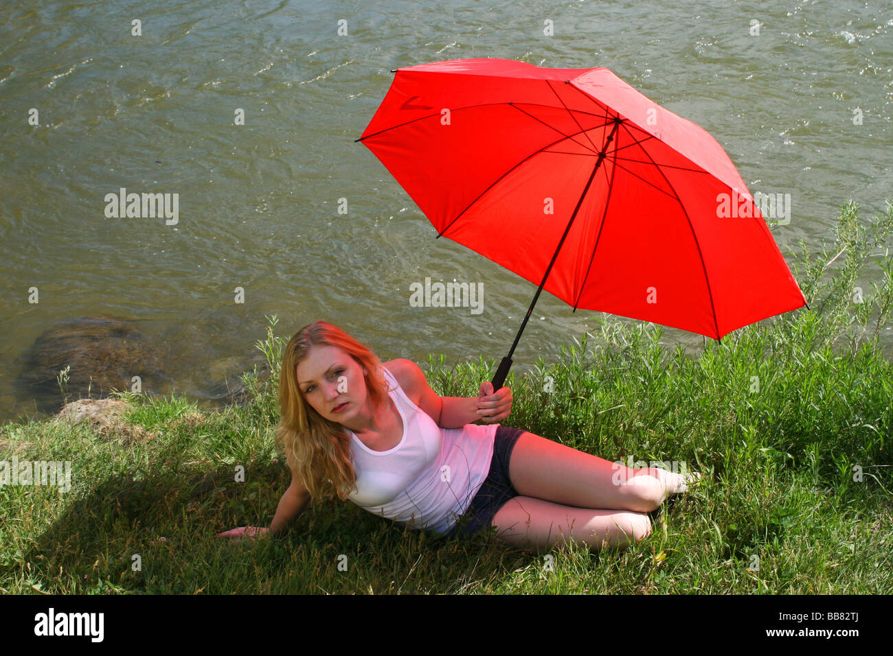 Kaukasische Frauenporträt entspannend in einem Park unter einem roten Regenschirm Stockfoto