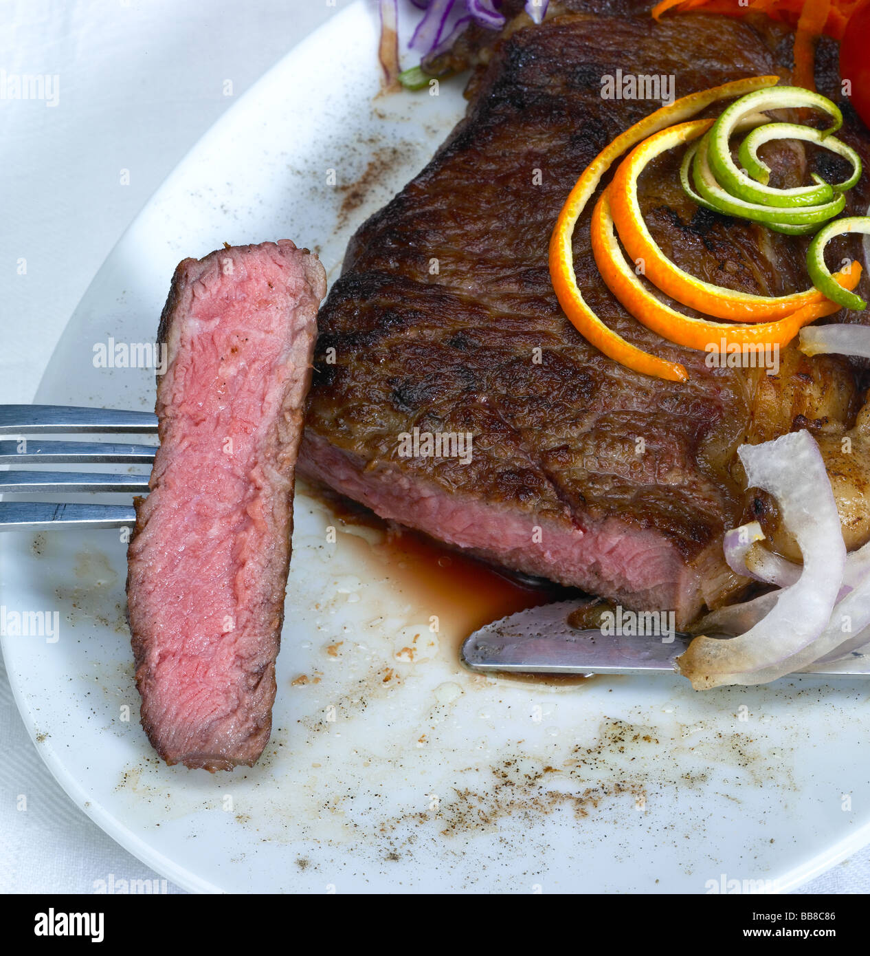 frische saftige Rindfleisch Ribeye Steak gegrillt mit Orangen- und Zitronenbäumen Peel auf der Oberseite und Gemüse neben Stockfoto