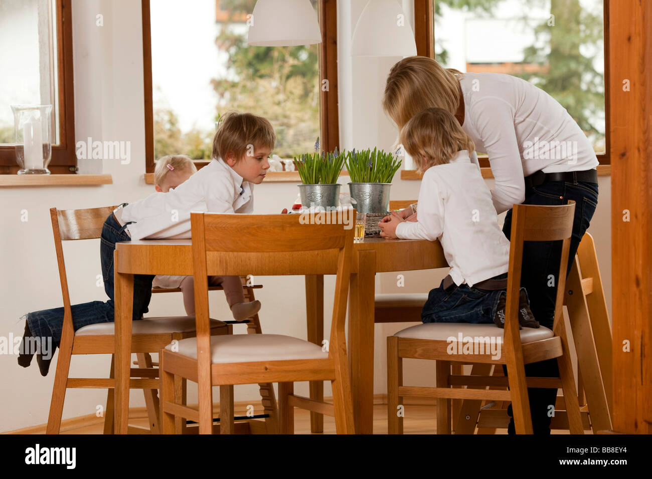 Mutter und drei Kinder, 1, 3 und 6 Jahre alt, am Esstisch Stockfoto