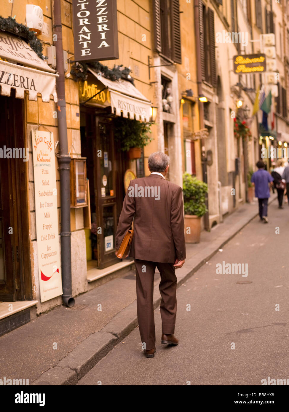 Rückansicht des senior Mann zu Fuß auf der Straße und tragenden Aktenkoffer; Rom, Italien Stockfoto