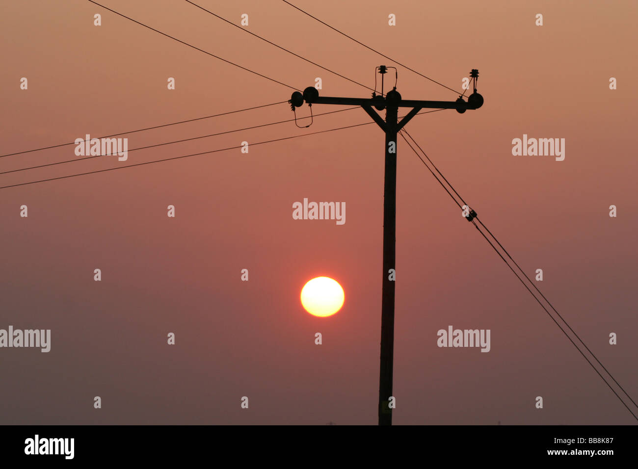 Macht Post mit Isolatoren, Kabel und Sonnenuntergang. Stockfoto