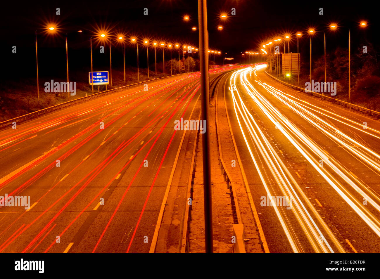 M1-Autobahn-Brücke in der Nacht, Stanmore, Schlieren Lichter oder Autos mit Schild mit der Aufschrift "The North" und "Luton 20' Meilen Stockfoto