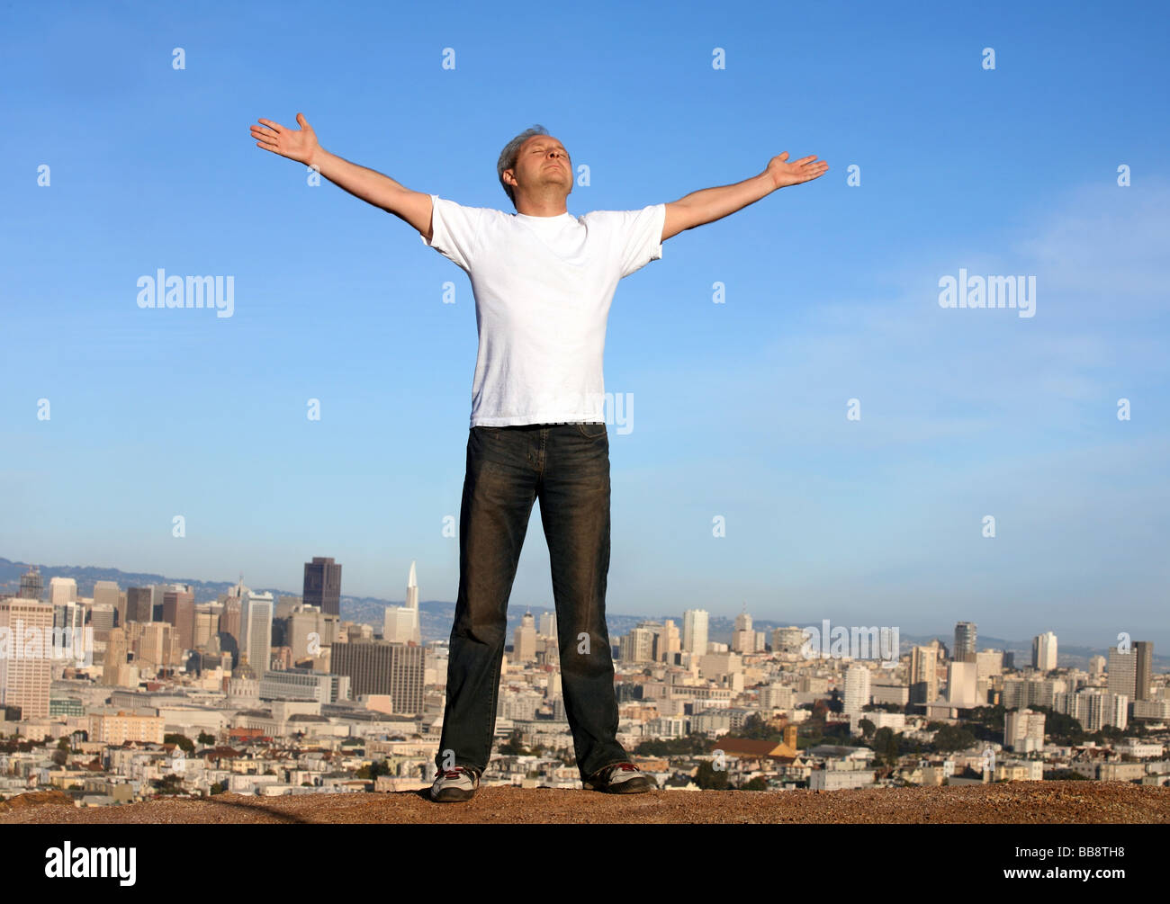 Ein Mann steht auf einem Hügel mit Blick auf San Francisco seine erhobenen Armen Stockfoto