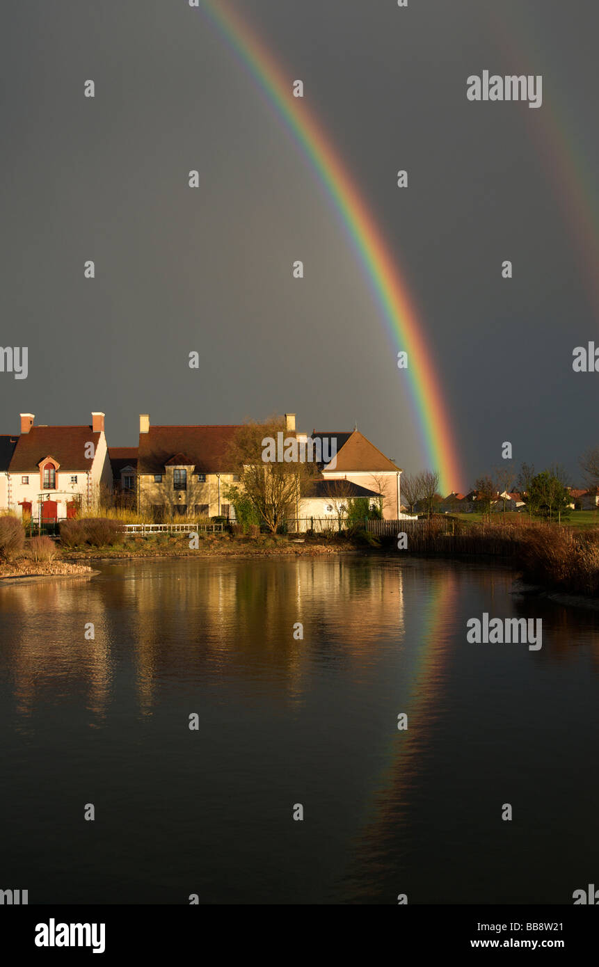 Dramatische Schwarz mit doppelter Regenbogen Himmel und spiegelt sich im Teich Nordfrankreich Stockfoto