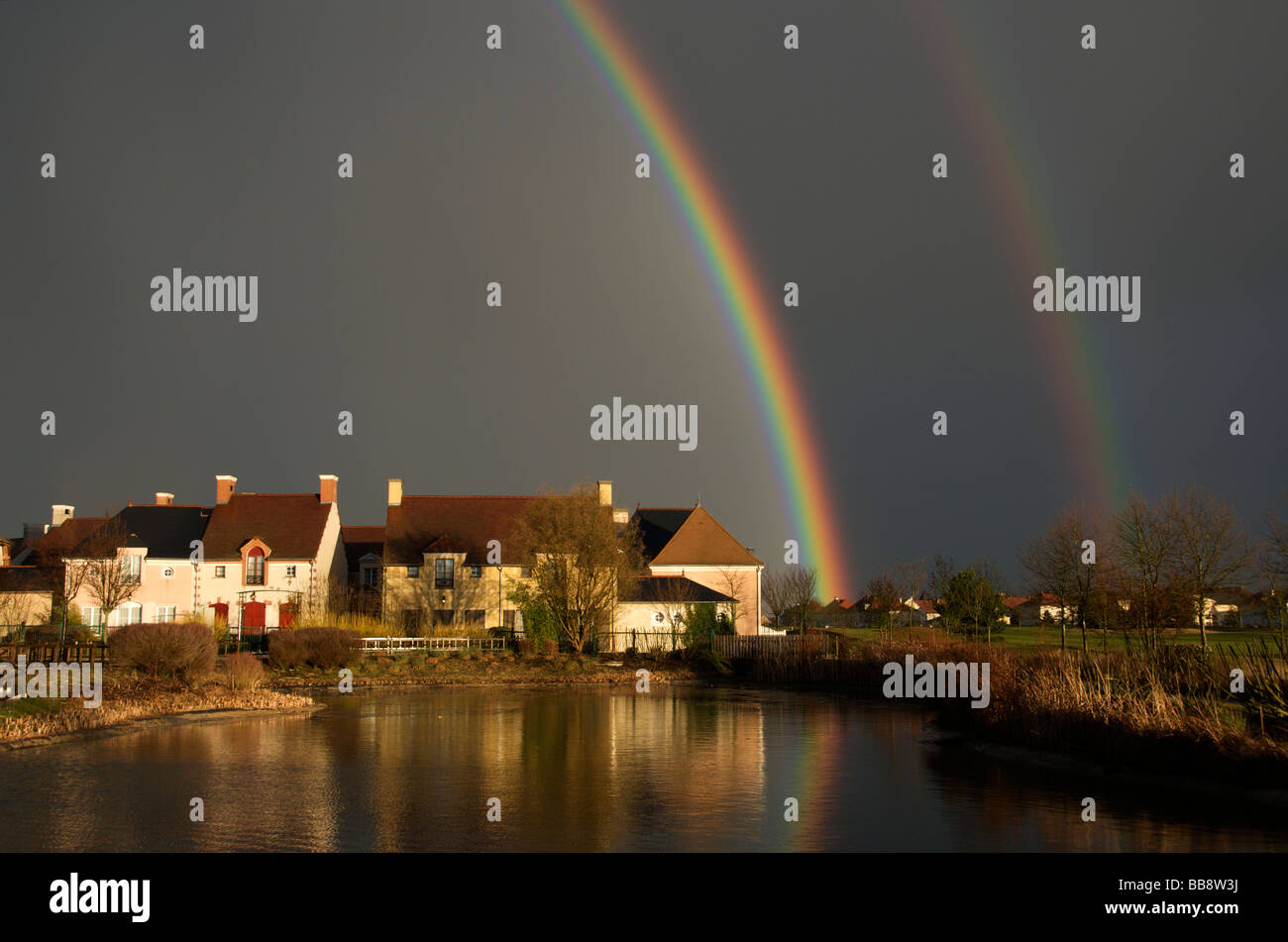 Dramatische Schwarz mit doppelter Regenbogen Himmel und spiegelt sich im Teich Nordfrankreich Stockfoto