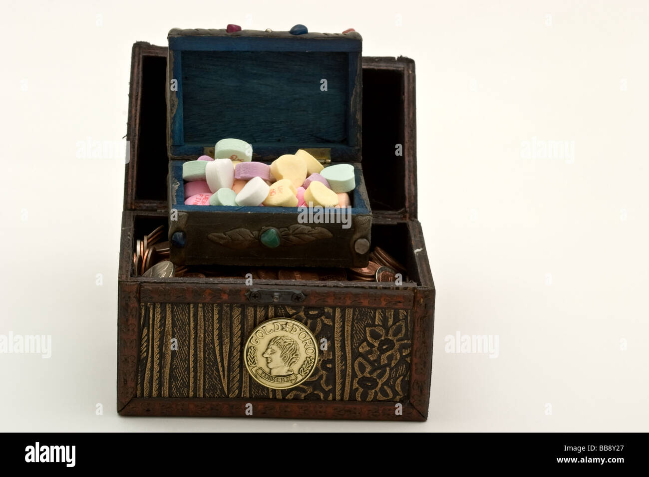 Kleine Schatzkiste gefüllt mit Süßigkeiten auf eine größere Brust Fille mit amerikanischen Münzen in Herzform Stockfoto